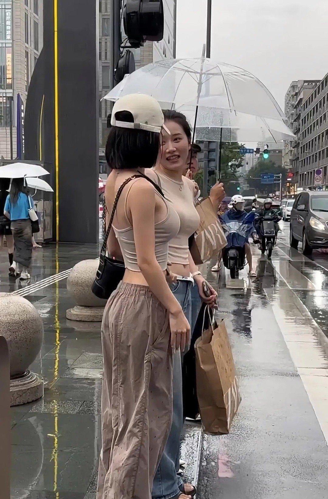 下雨天街头偶遇两位小姐姐，氛围感拉满！
 
地面湿漉漉的，透明雨伞撑在头顶，两人