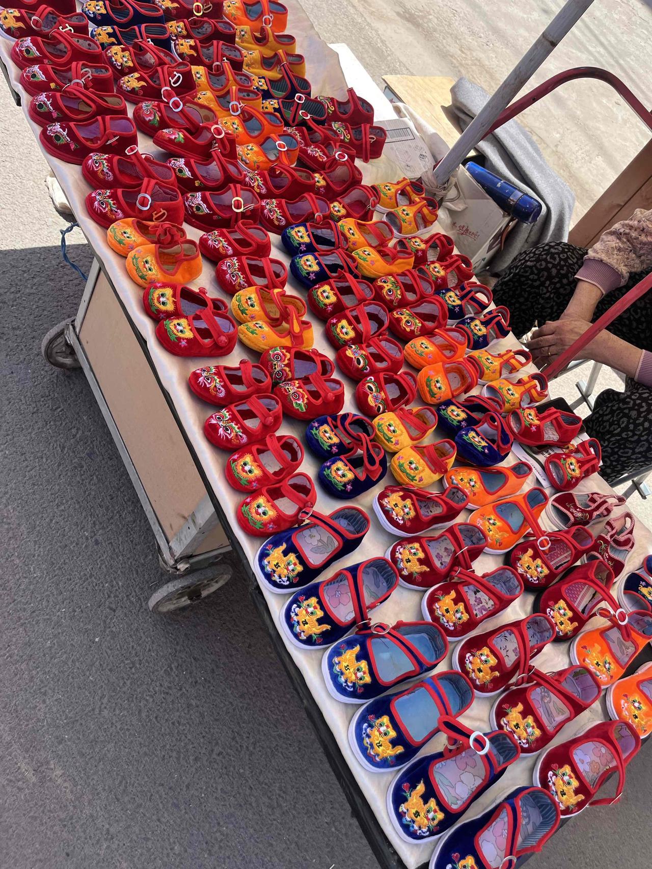 农村大集上的儿童布鞋摊位，大娘自己做的布鞋，看上去又舒服又喜庆。

现在很少有人