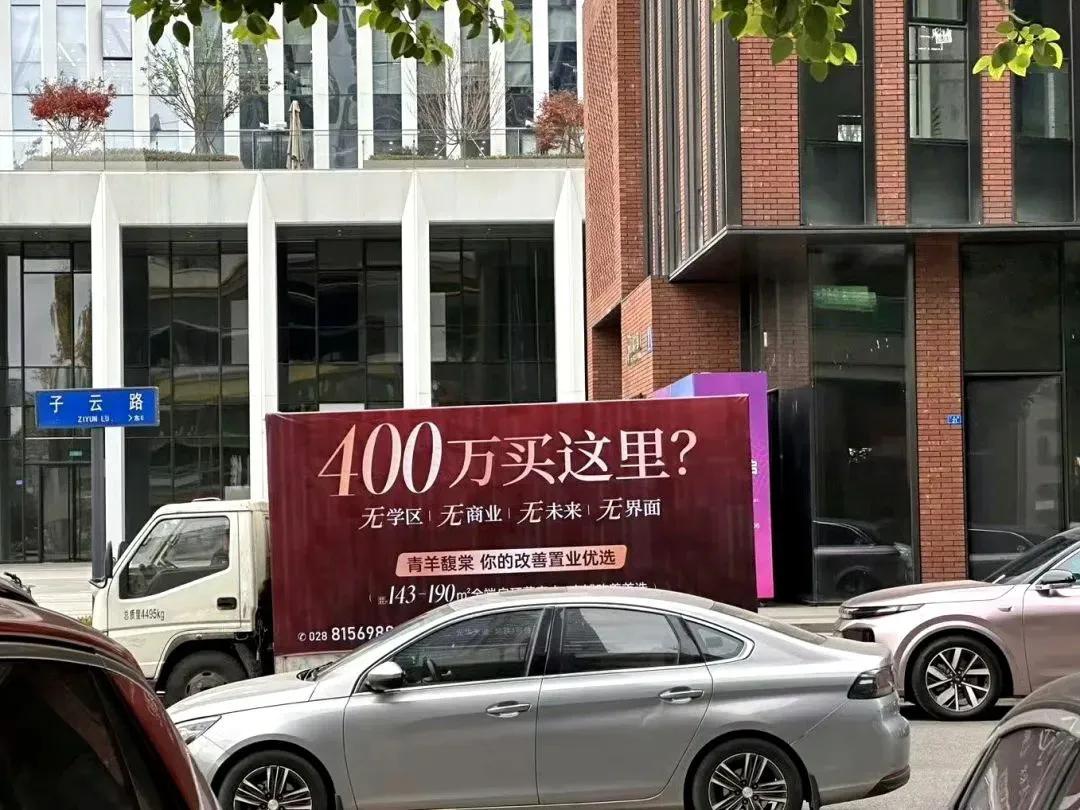 一辆广告车停在子云路边，上面的广告写着：400万买这里？无学区，无商业，无未来，