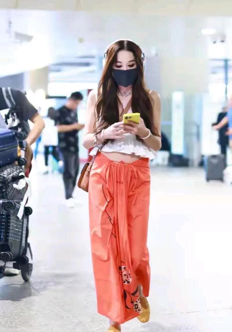 温碧霞年过半百不服老，白色吊带+橘色半裙走机场，时尚靓丽，尽显曼妙好身材!