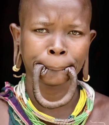 这是一名漂亮的非洲“唇盘族”女孩，她嘴里含着的并不是香肠，而是自己的下嘴唇，女孩