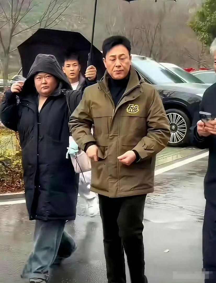 女助理半个身子淋着雨，张颂文却在伞下悠闲嗑瓜子。 