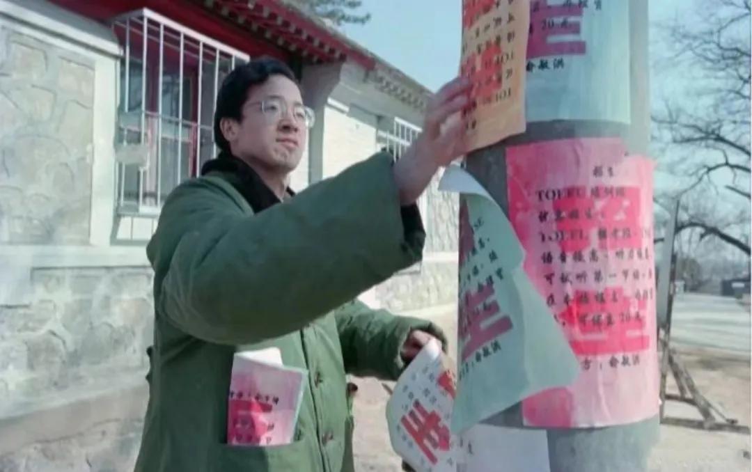 90年代，俞敏洪在北京街头，张贴小广告，镜头中的他穿着一件军大衣，戴着眼镜，看起