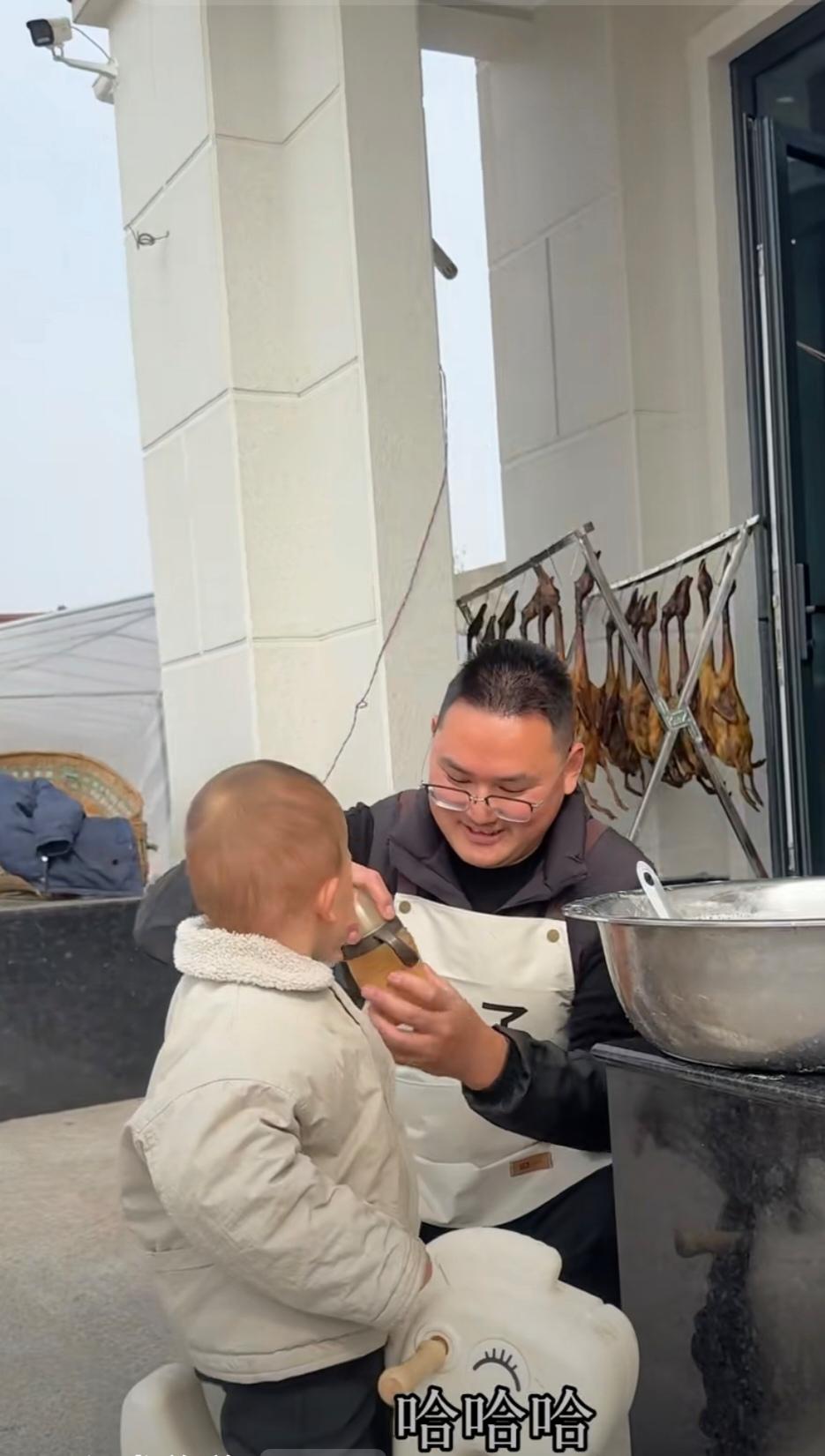 小二娃在做豆腐，小成成这个可爱的小朋友在旁边观看着爸爸，小二娃问小成成，“你要喝