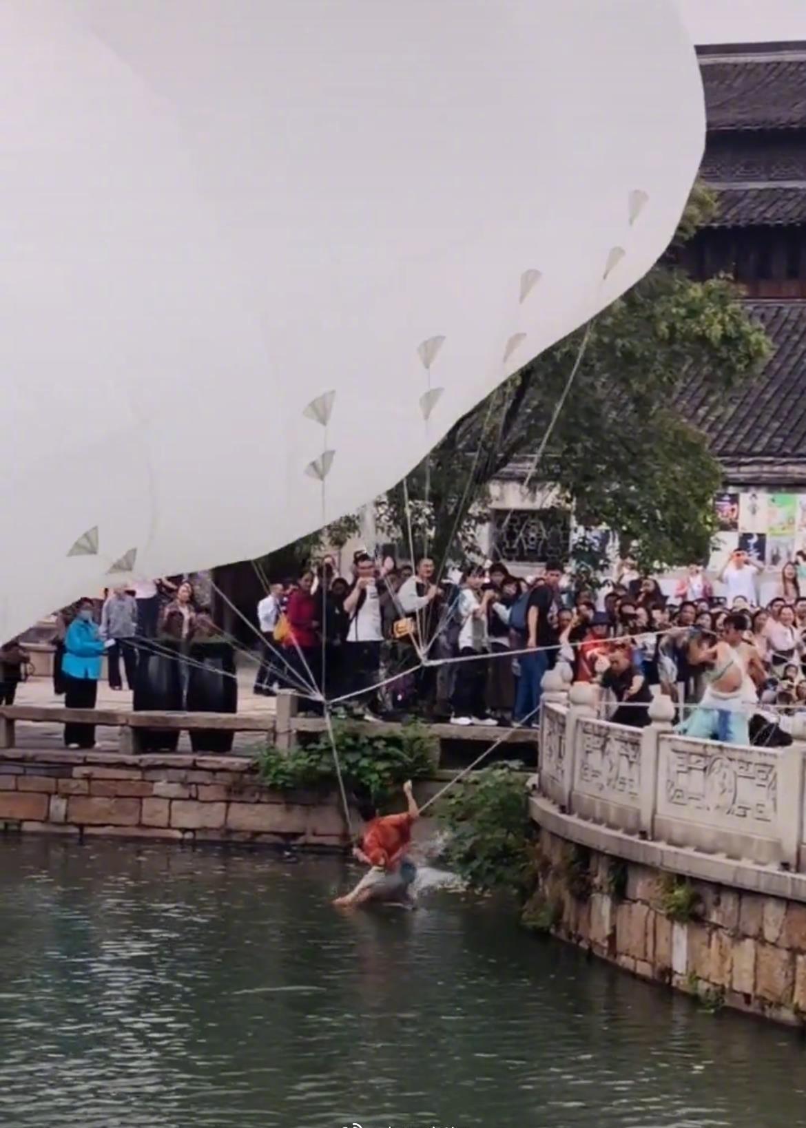 社交平台的视频显示，女演员身上系了很多绳子与上方的白色气球相连，地面的团队成员控