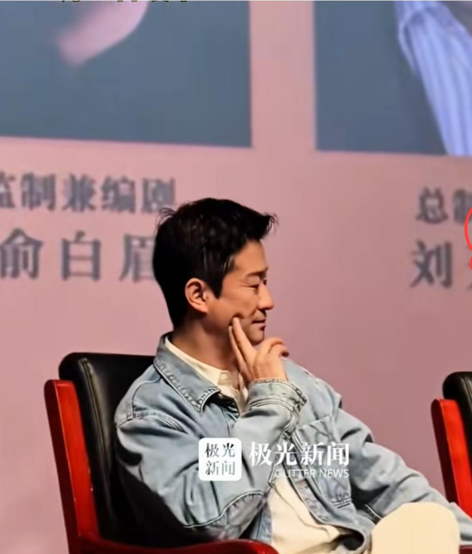 吴京在电影《镖人》校园活动中，吴京坐在椅子上，两根手指撑着脸后，松下手指，脸上深