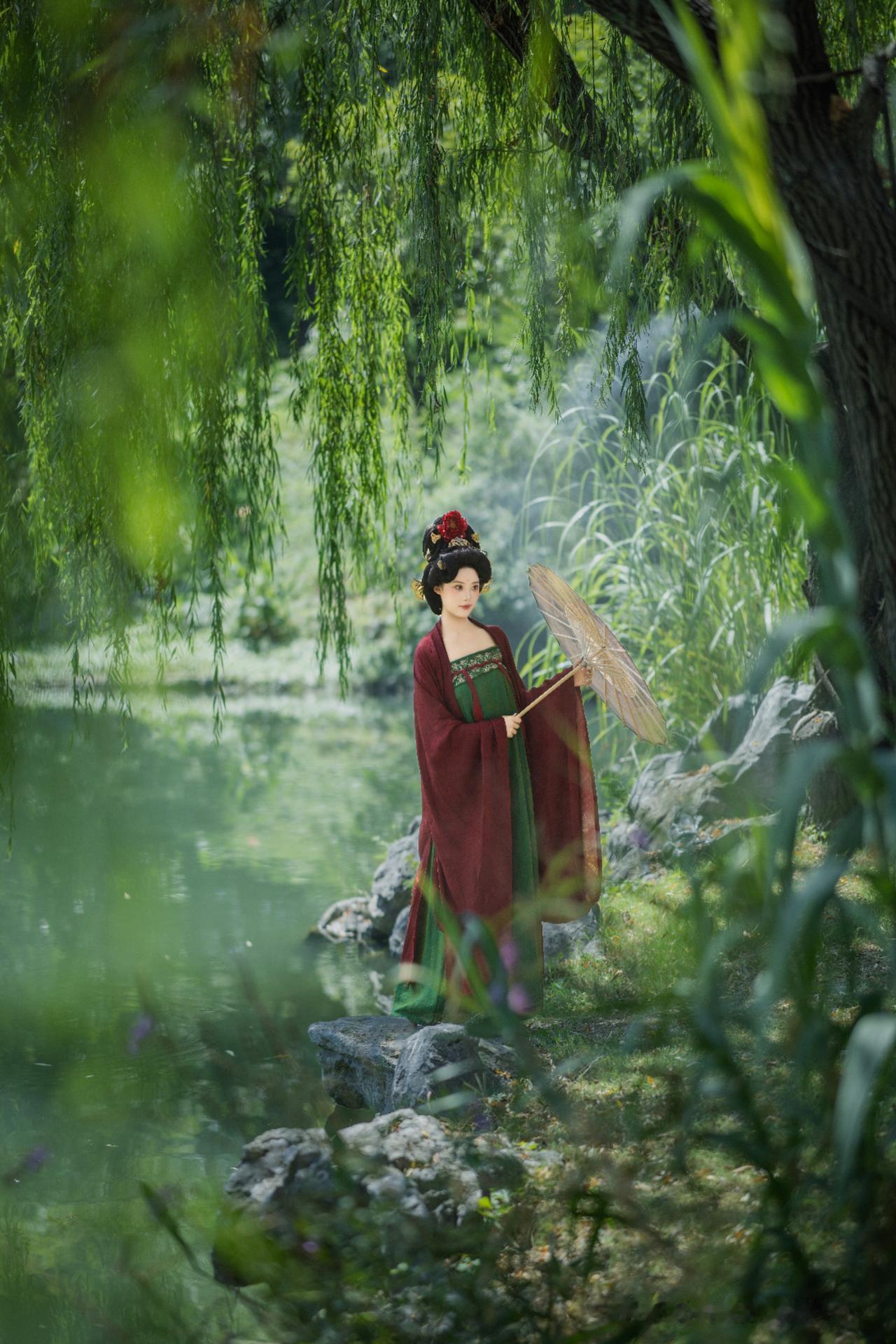 柳荫深处，绿裙红衣佳人持伞而立，仿佛穿越千年的温柔梦。绿裙仙韵