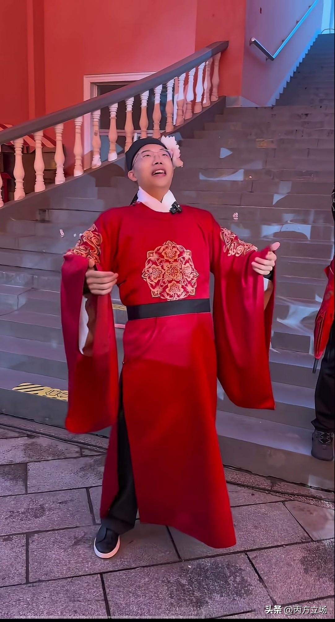 近日，郭有才出席某庆典活动，一身大红袍长衫格外抢眼，头戴小的粉色花饰，文质彬彬，