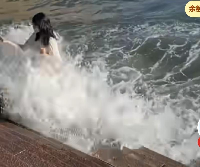 女子站在海边拍照，被浪打倒在地，
不立马起身逃生，
却坐在地上生闷气，
网友说，