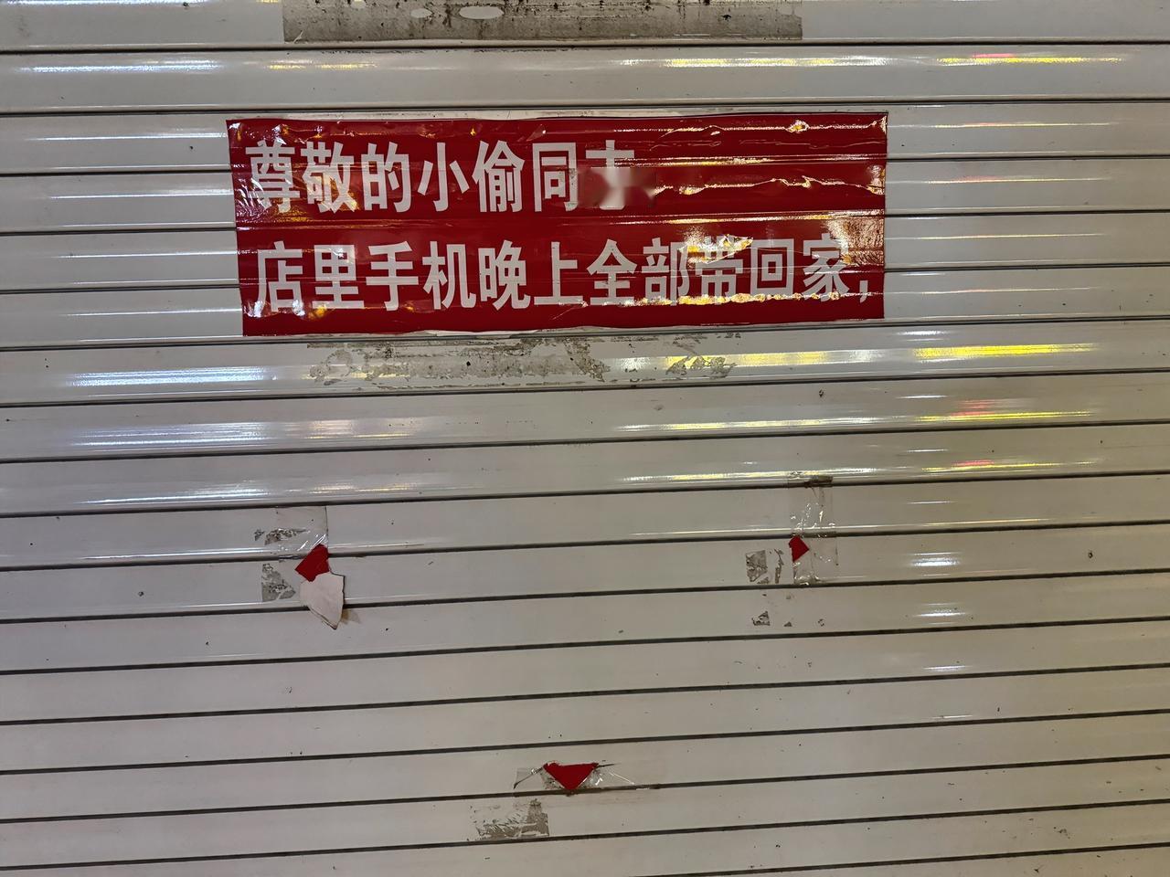 “尊敬的小偷同志，店里手机晚上全部带回家”——这家手机维修店卷帘门上红底白字的“
