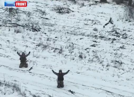 冰天雪地大荒野，2名乌军士兵跪在地上，举手向俄军无人机投降！背后灌木丛里，1名乌