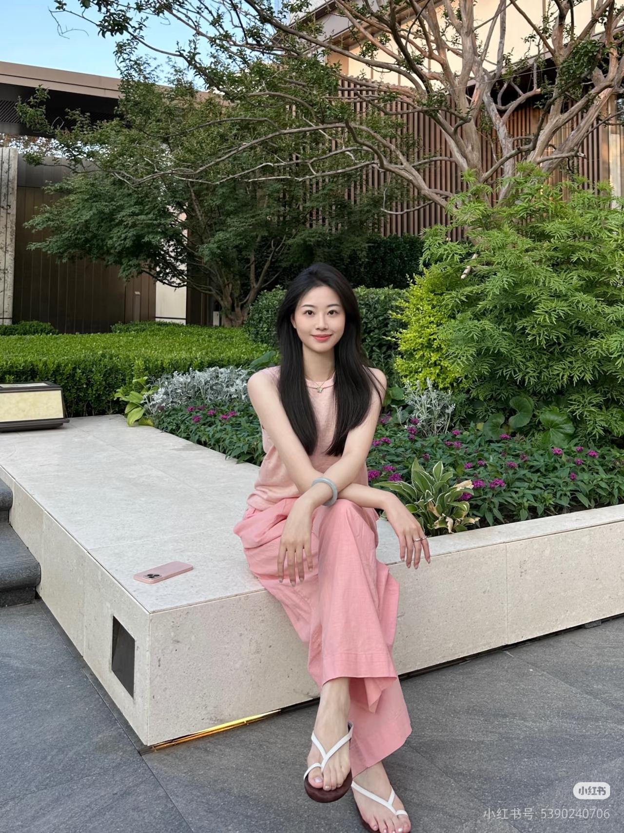 粉衣美人倚长凳，绿树芳菲映笑颜。