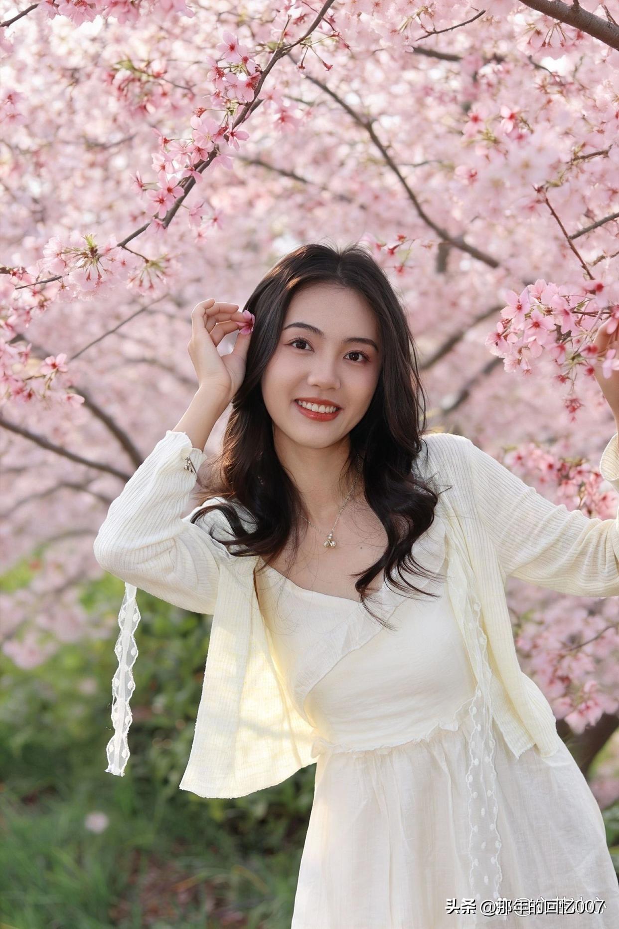 春日，樱花树下，一位甜美少女手持清饮，笑靥如花，那画面宛如梦幻之境。粉嫩的穿搭与