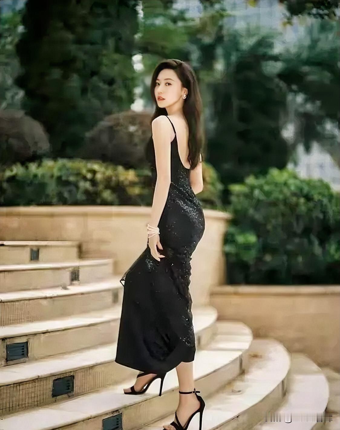 石阶蜿蜒，绿意轻拥。
黑裙曳地，星芒暗涌。
露背如弦，弹着晚风的歌。
高跟叩响，