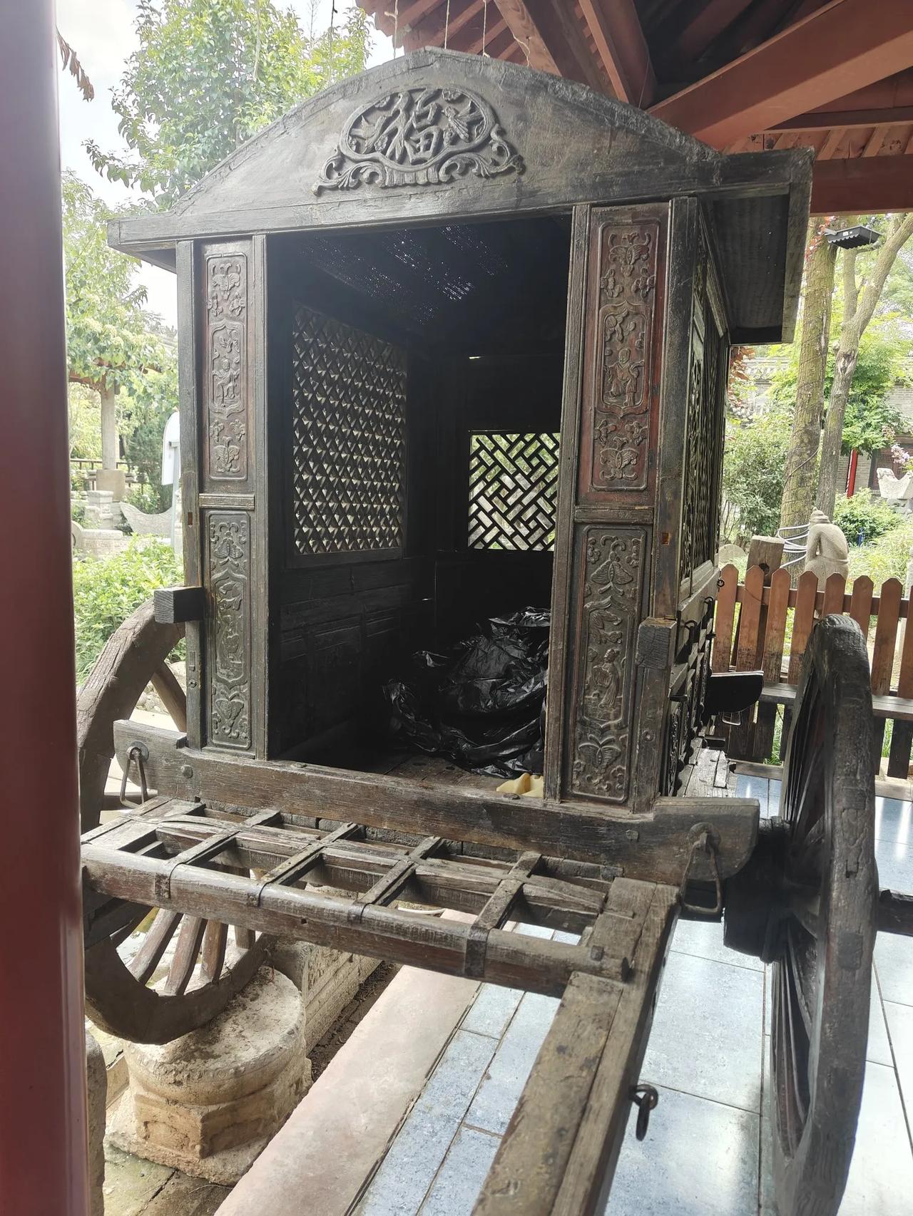 庭院廊下停着一辆老马车，乌沉木纹里浸着百年的旧月光，顶檐那枚雕花“福”字，总在有