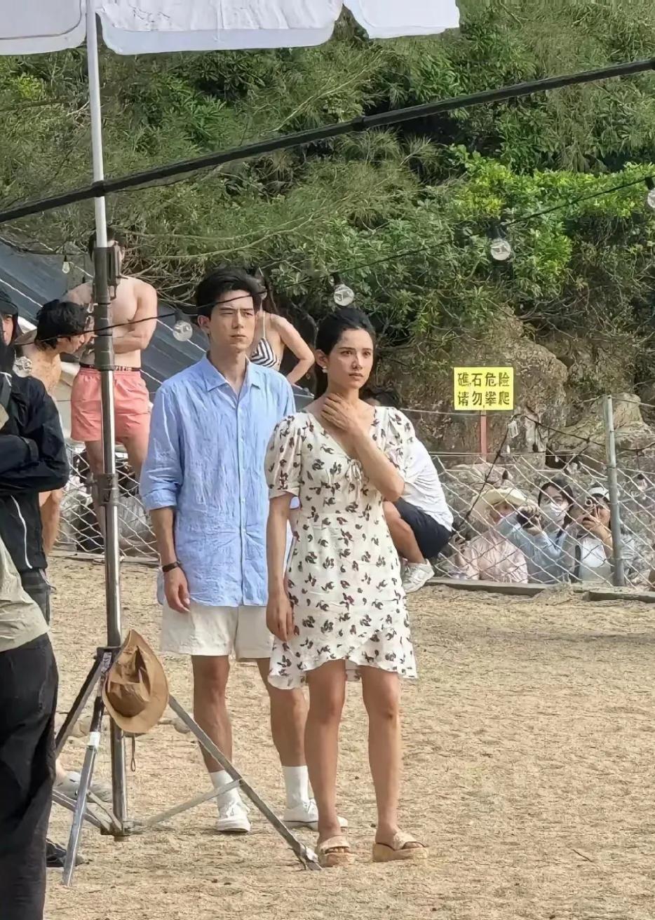 镜头中的李现疏眉小眼，耸鼻贝齿，长脸薄唇，发量惊人，淡蓝色衬衫皱皱巴巴；身旁的女