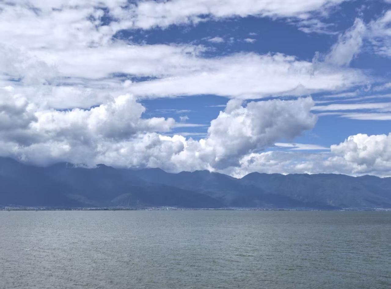 云南洱海，碧海连天，一望无际，天空白云连绵起伏，海岸两边被山峦围绕，云海相接形成