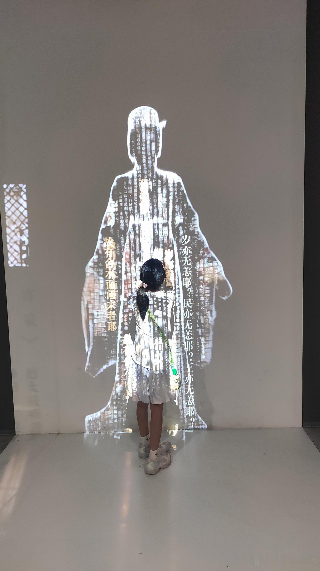 小朋友在墙前玩投影游戏。儿童墙面游戏