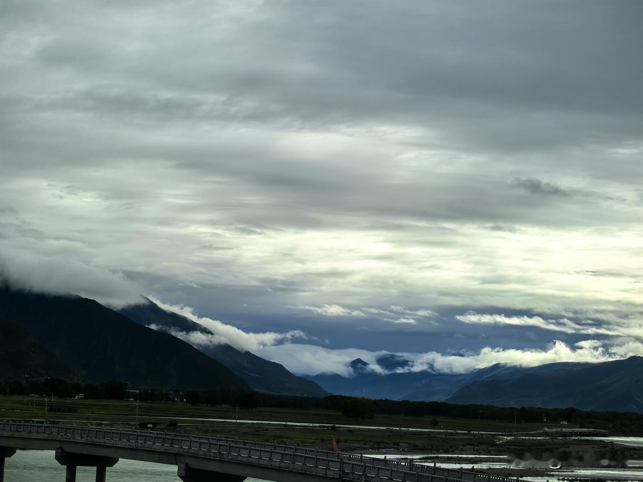行驶在拉林高速，河谷山峦连绵，云雾漫上山头，河水蜿蜒，藏地山野缓缓向后掠过。