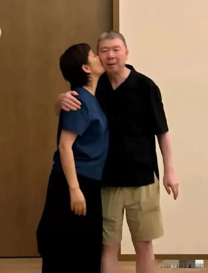 这是国内某著名导演和他的老婆秀恩爱的情景，他的老婆情不自禁的给他一个湿吻，这张照