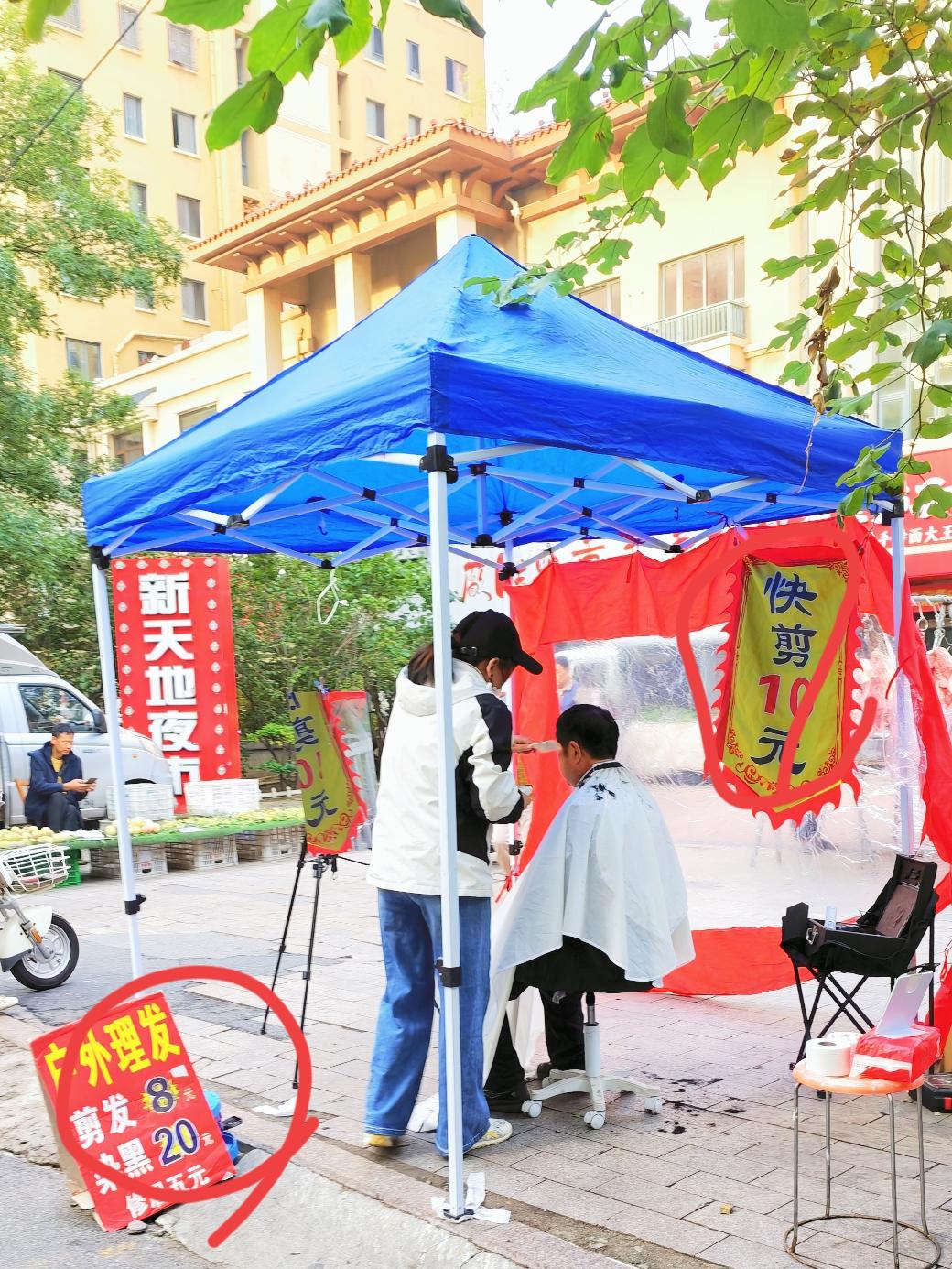 在<宝龙广场早市>东边的路口上，看到有户外理发的摊位。
每次走到这里，看到前来理