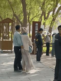 景区内绿树下，导游正对着自己一方的团员们讲解着景区的历史与众不同，来来往往的游客