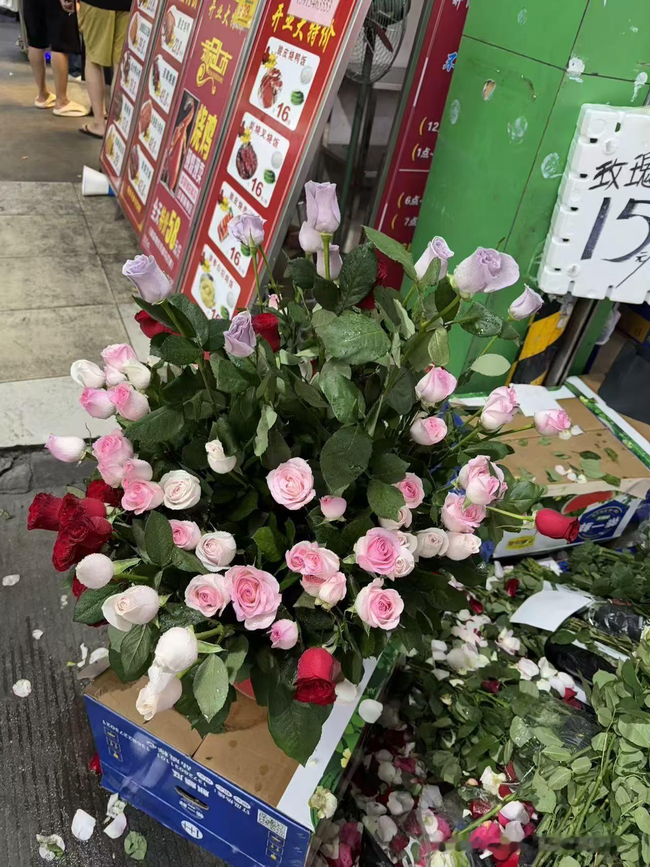 路过街边小店被一丛玫瑰绊住脚步，标价十五元一把，各色花束随意堆放在纸箱上，散落的
