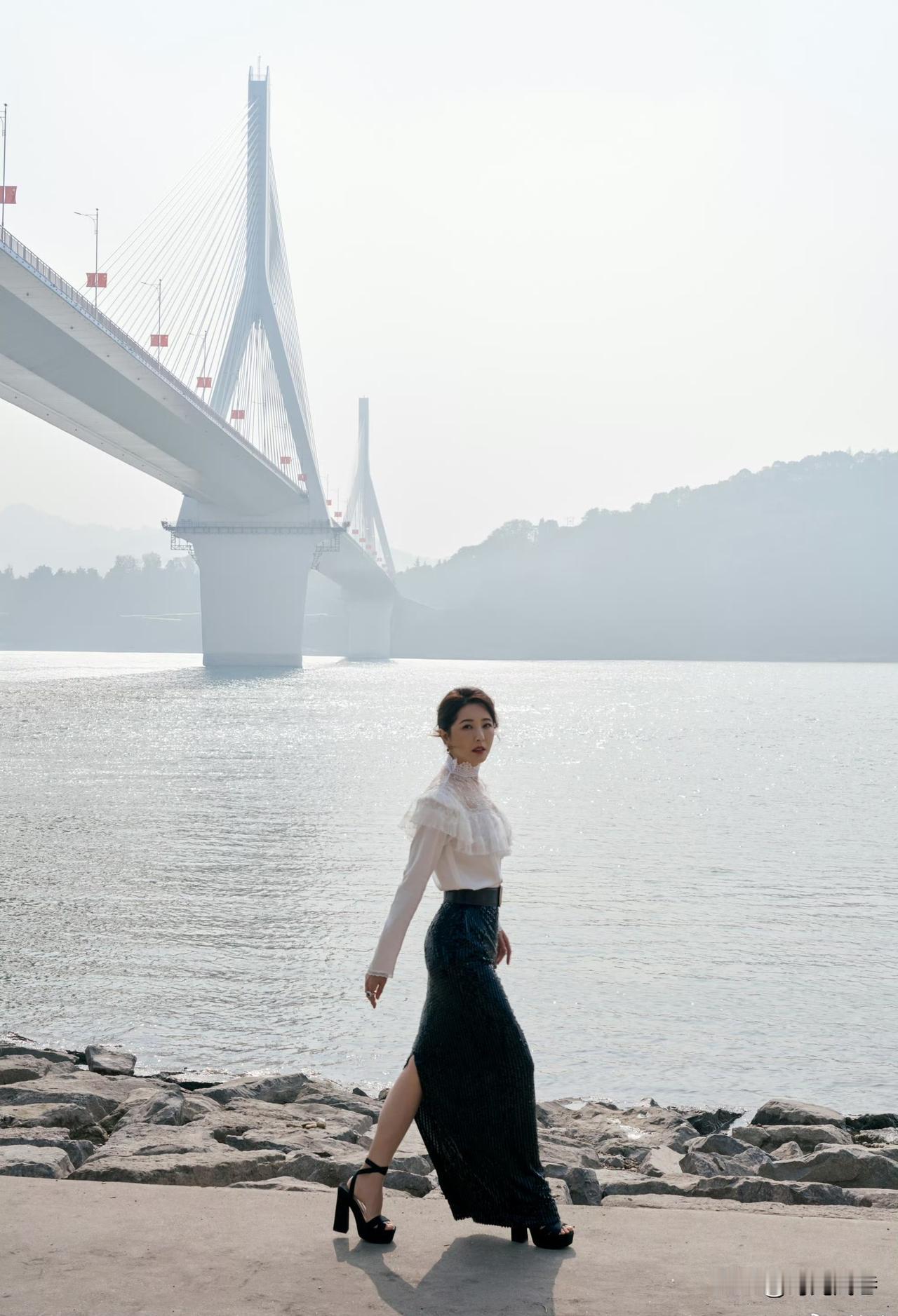 回到家乡在长江边拍照的曾黎，白衣打配黑裙。成熟稳重，优雅迷人。曾黎冻龄秘诀