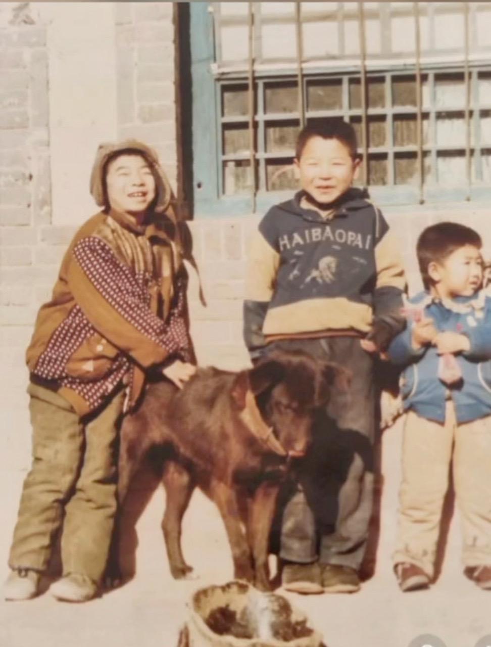 看这张老照片中少年的穿着，或许是拍摄于2000年左右，图中的黑狗耳朵较大，它在低
