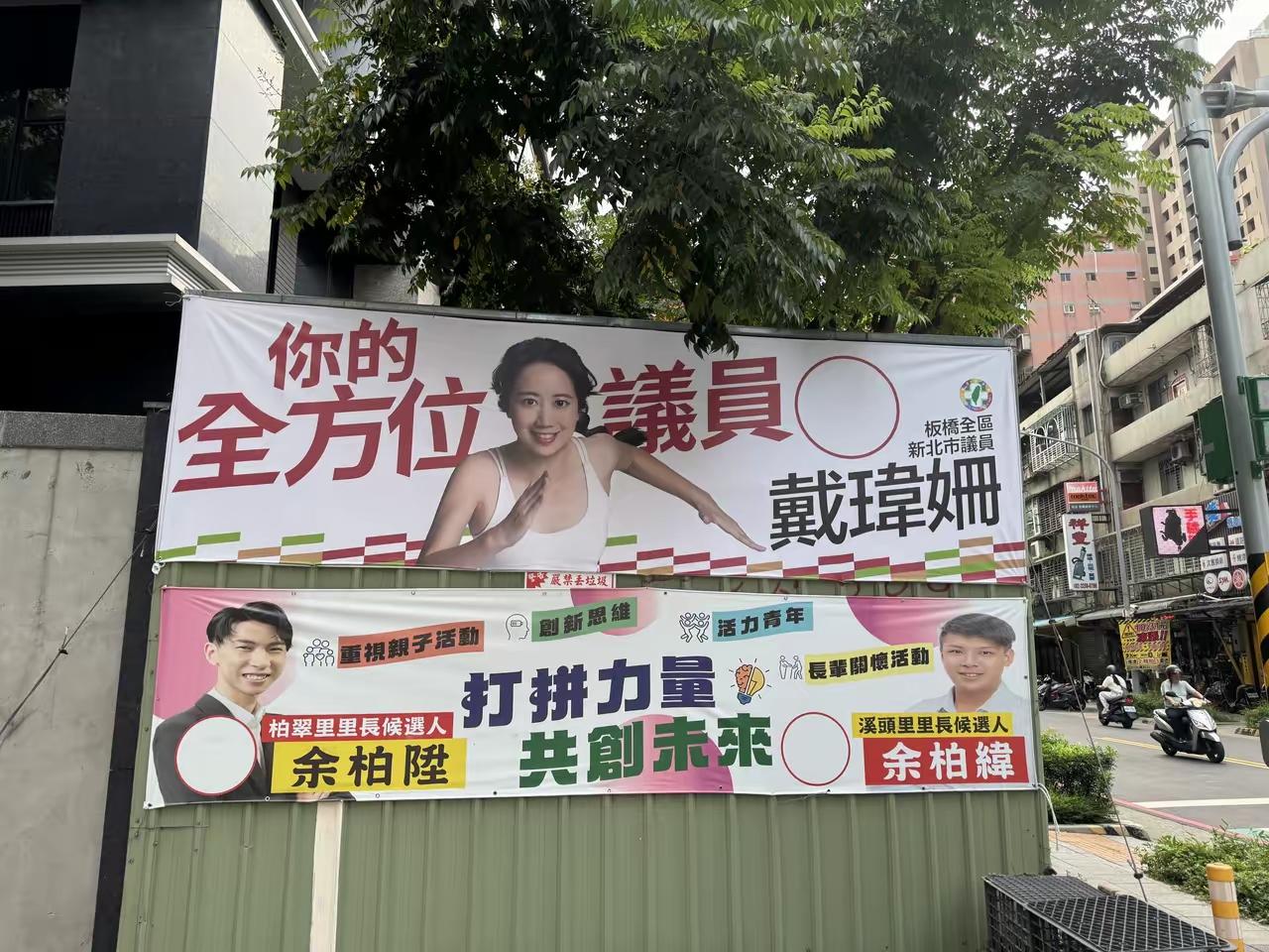 这是在台湾新北市板桥区在街上橱里矗立的候选人看板，我们看到了上边的民进党发言人戴