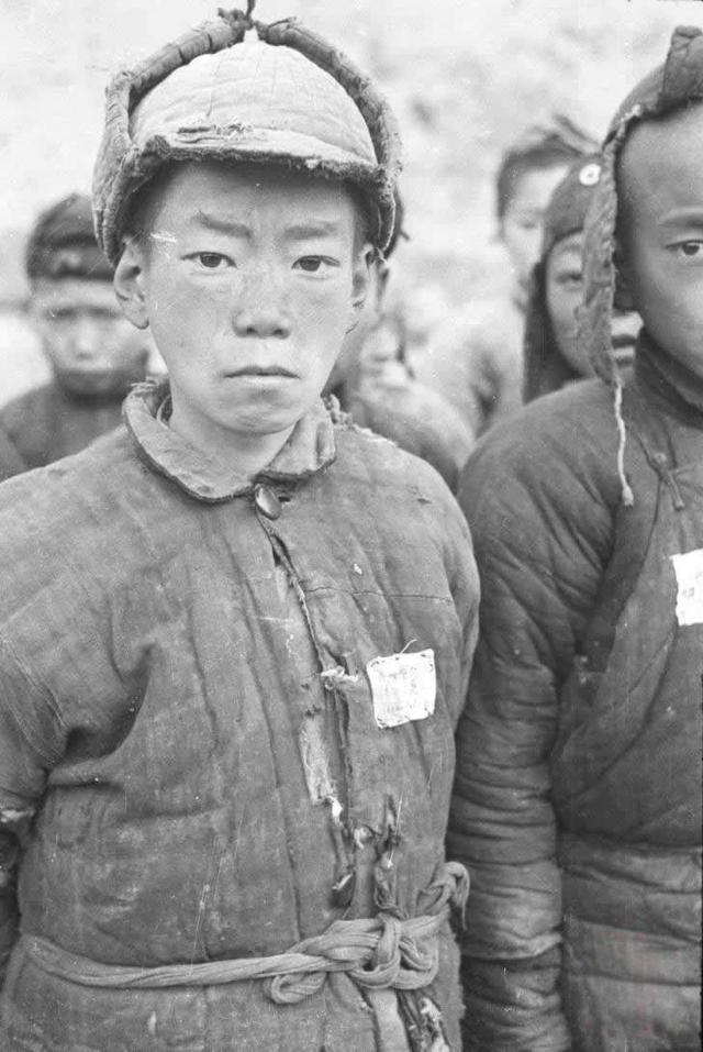 这是一张展现抗战时期西安少年兵肖像的照片。少年身着破旧、缺乏规整样式的衣物，因物