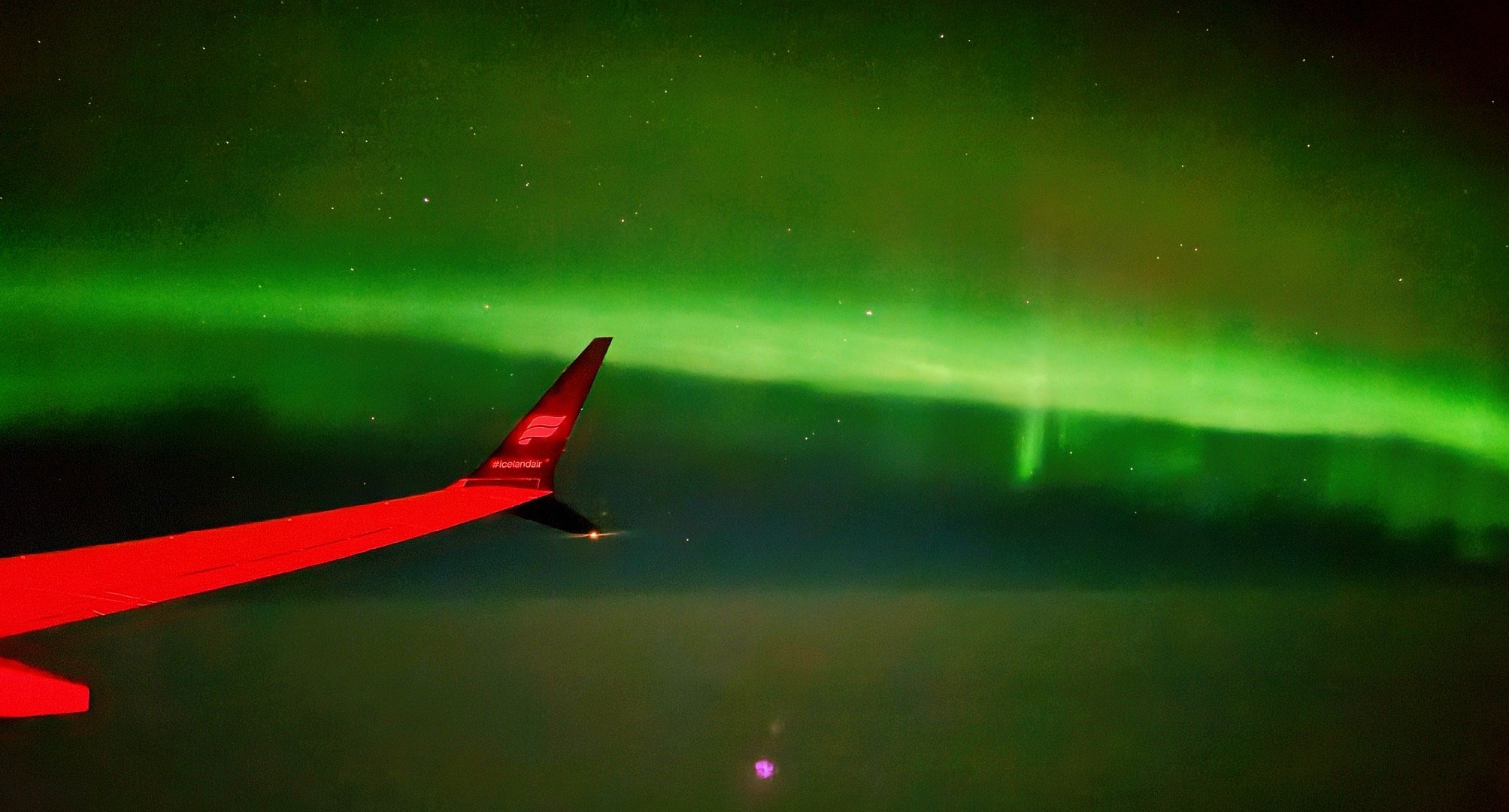 团队平安落地冰岛。舷窗外的极光直接“开屏”，手机直接拍下。冬日摄影之旅的第一份好