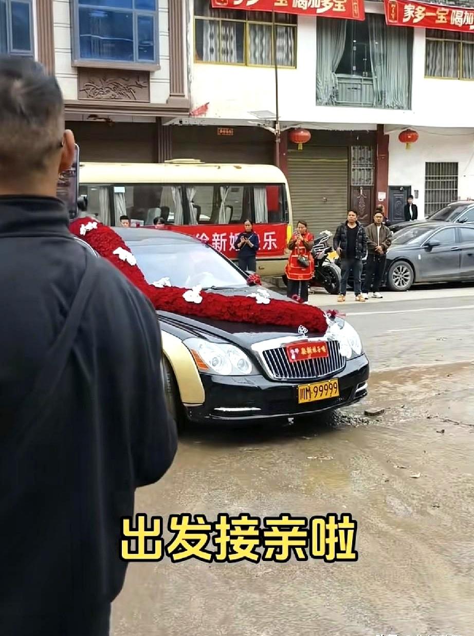 黑金婚车挂着川M·999999的牌子，车头上铺满红玫瑰，路过小镇时好多人举着手机