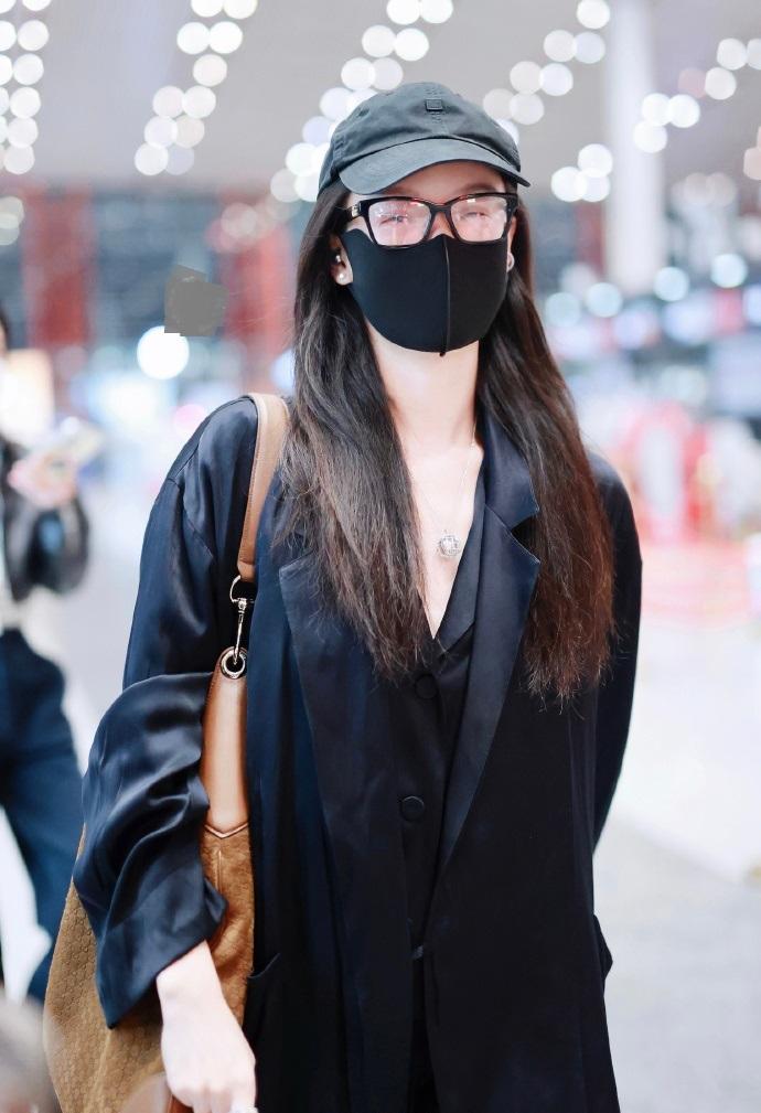 今天倪妮现身北京机场，她里面穿黑色短西装，下身搭配黑色阔腿裤，外面穿着黑色的风衣