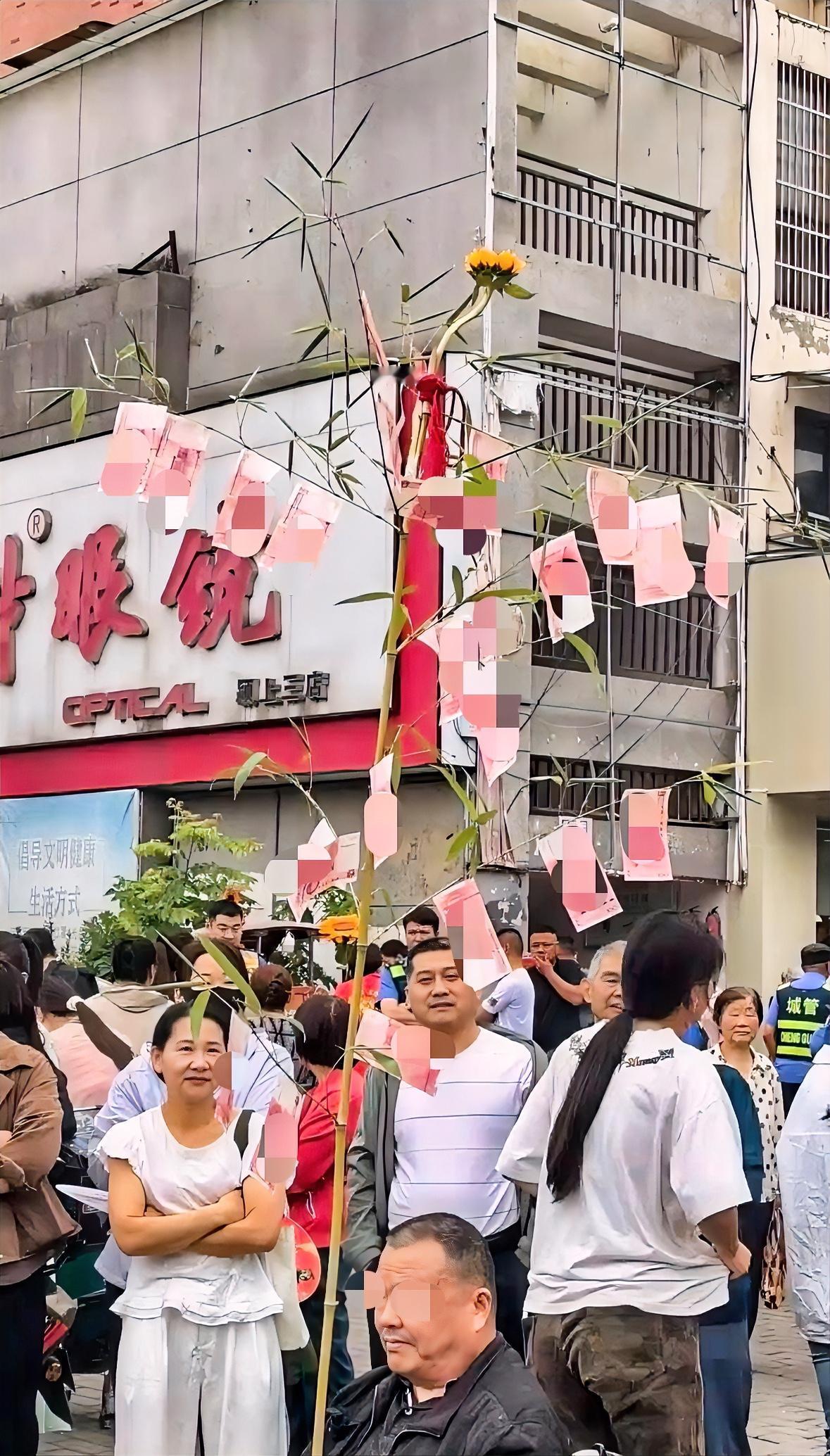 高考第三天场外家长把26张百元人民币绑在竹子上为孩子加油。

高考家长候场花样多