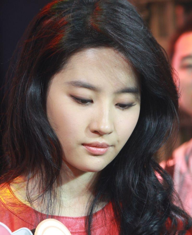 刘亦菲身着红色皮质上衣，利落的圆领剪裁贴合颈部线条，皮质材质硬朗有质感，鲜艳的红