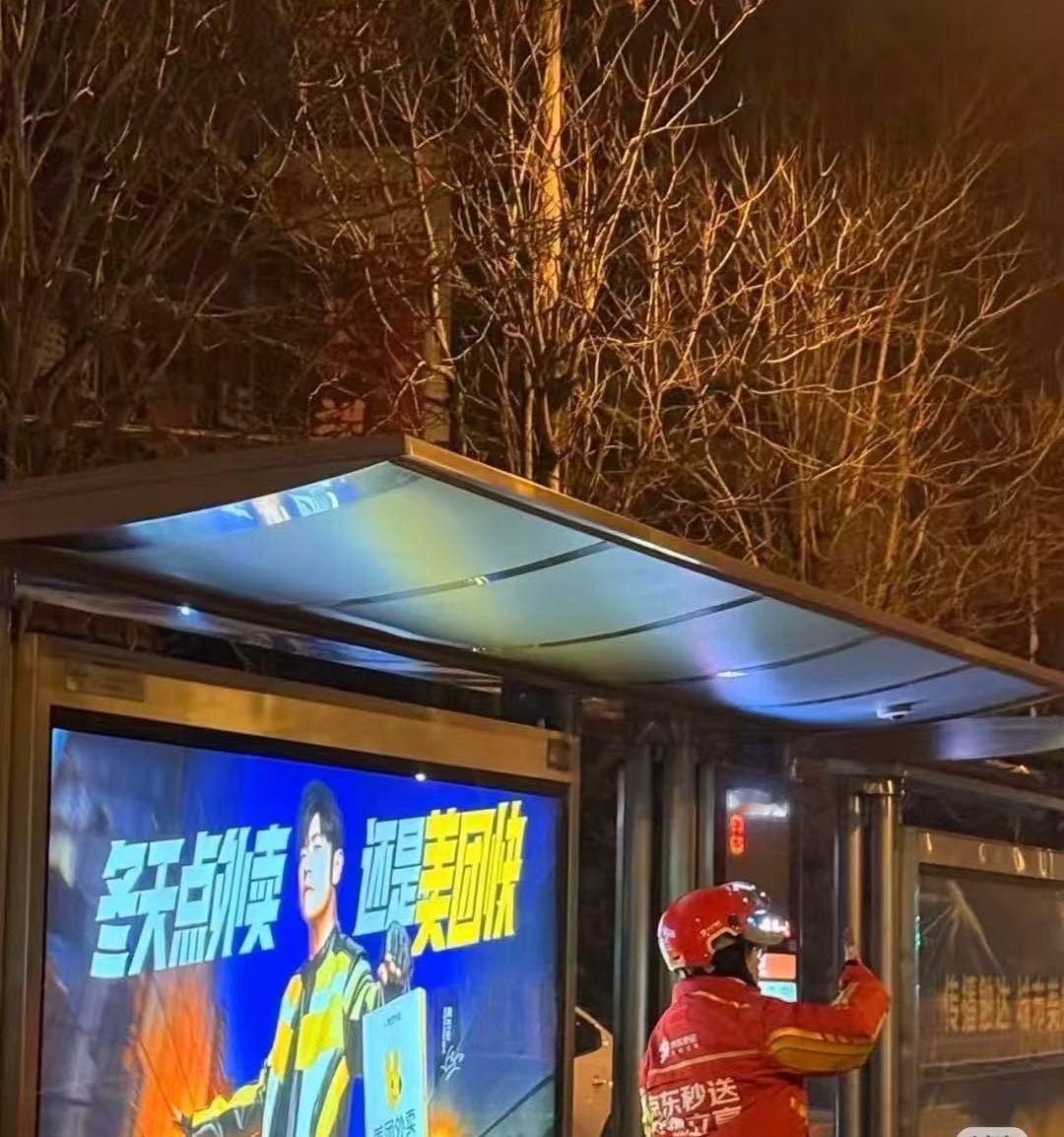 建议和平大使考虑一下周杰伦 深夜街头，捕捉到配送员在周杰伦的广告牌下，举起了手机