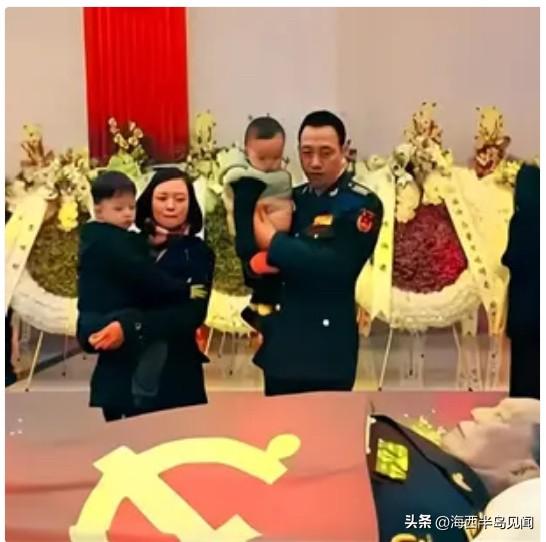 这是董万瑞将军的送别现场，家人怀抱年幼的孩子前来吊唁。他是98年抗洪总指挥，带领