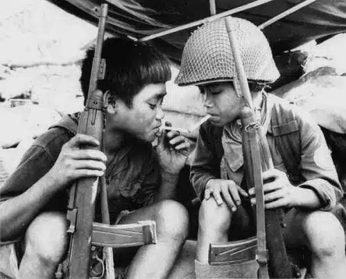 两名南越童兵在等待北越进攻时一起抽烟，越南战争，1965-1975年