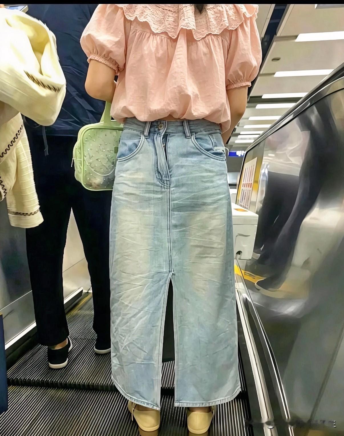 地铁站，扶梯上
我总感觉这位女士的裙子穿反了
首先，拉链在后面
其次，兜兜的方向