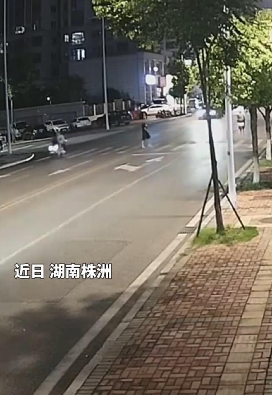 近日，湖南株洲的晚上。男子过斑马线，往左边望了望，一辆行驶的白色轿车离自己较远，