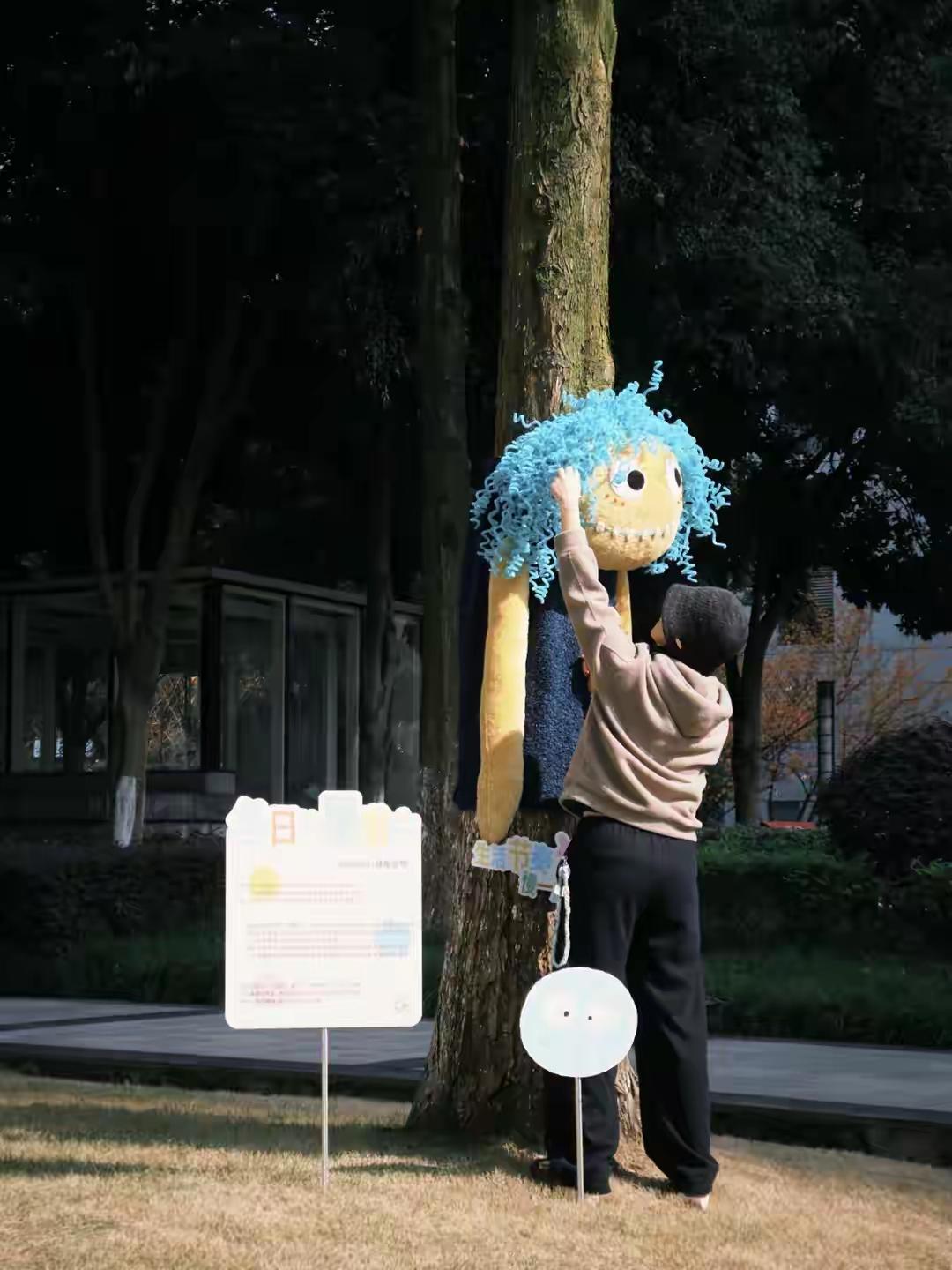 近日，重庆渝兴广场里许多大树都被娃娃外套包裹起来，有人称赞这一设计奇特有趣，前来