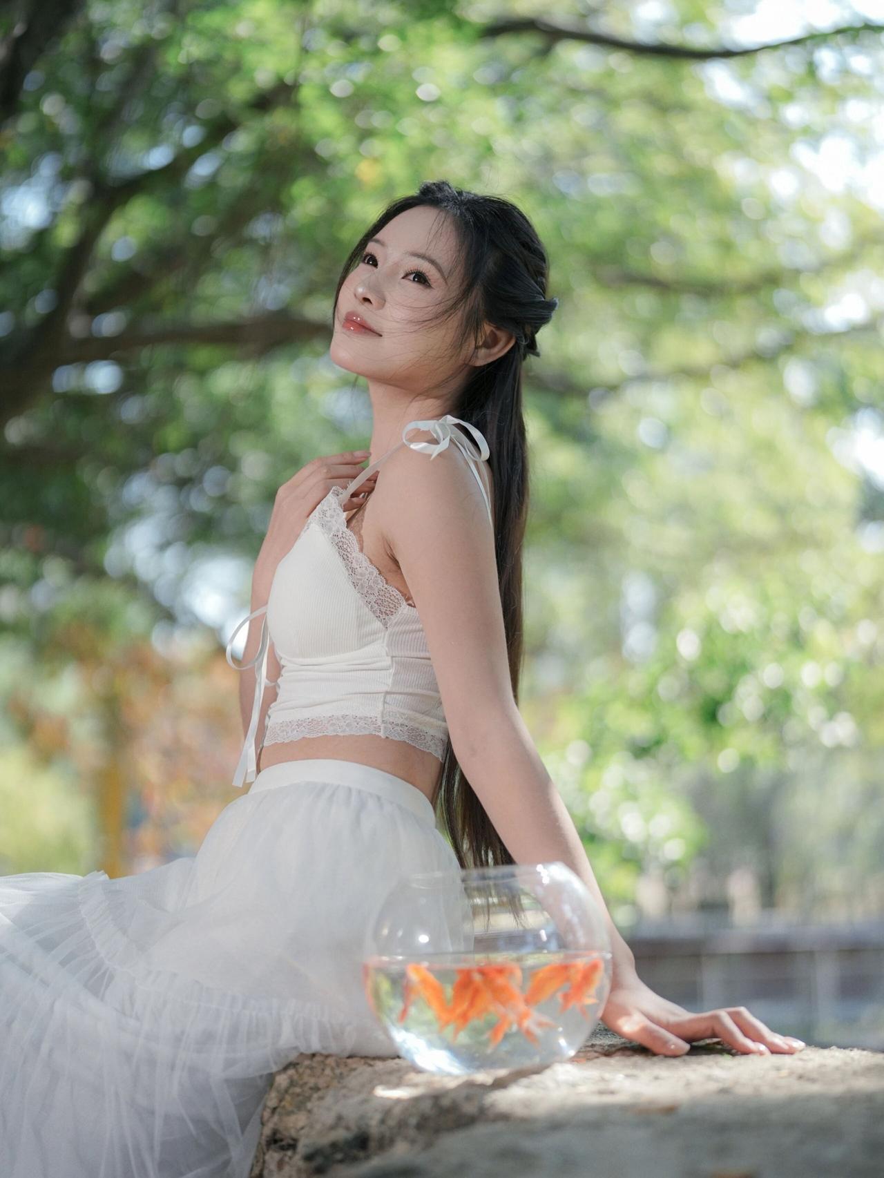 画面中的少女身着一袭纯白吊带纱裙，蕾丝花边点缀其间，轻盈的裙摆随风轻扬，尽显温柔