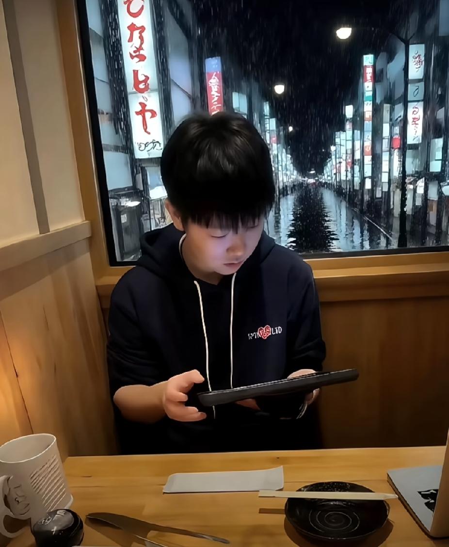 刷到这张抓拍，一下子就被打动了！
窗外雨夜街道，屋内暖光融融，莎莎安安静静坐在座
