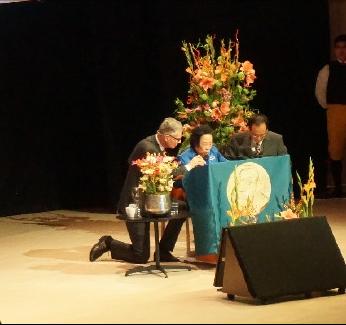 2015年，诺贝尔获奖者屠呦呦受邀发表演讲，然而，由于话筒线不够长，她只能弯着腰