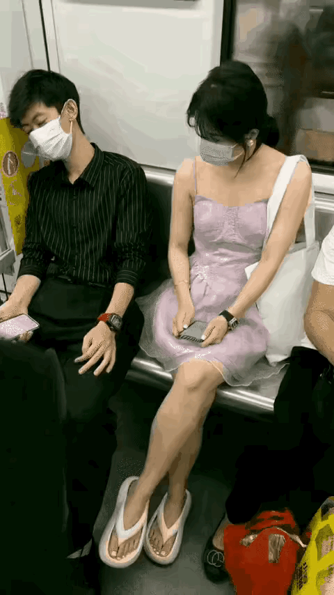 轻轨车厢帅气男士拿着手机有些困意在座位上睡着了，邻座年轻女士用手碰触他手机几下进