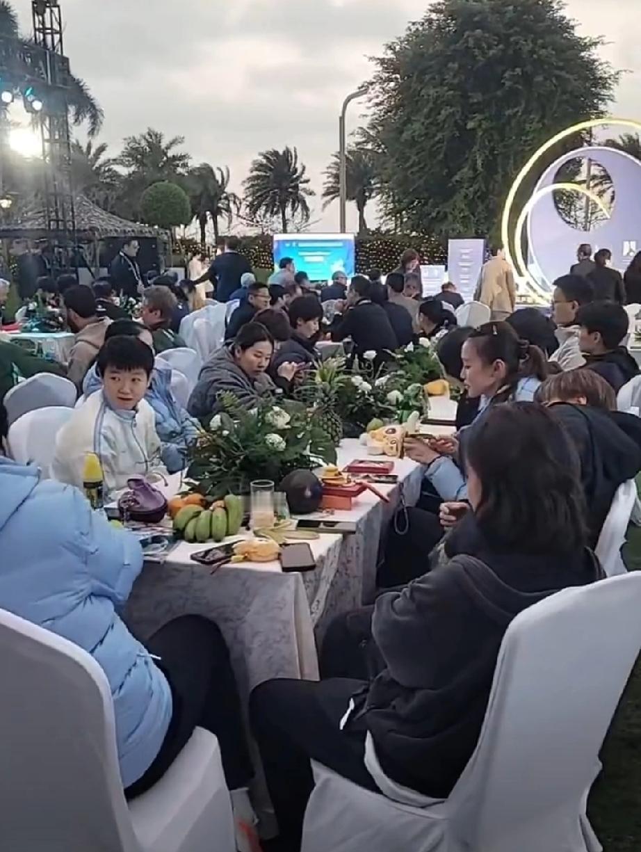 海口亚洲杯欢迎晚宴现场，国乒女队集体坐一桌。王曼昱低头认真看手机，孙颖莎与队友热