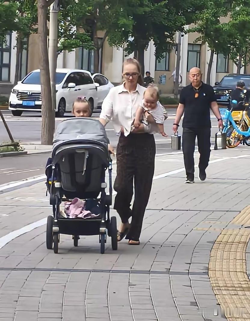 这个在北京生活的外国女人，一个人带三个孩子上街，婴儿车上躺着一个小的，车边上站着