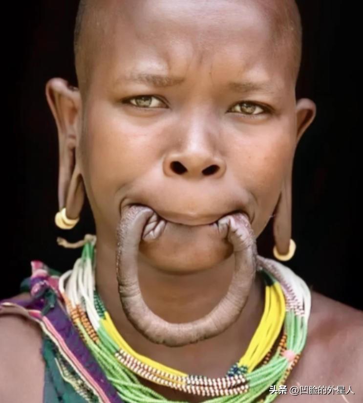 这是一名漂亮的非洲“唇盘族”女孩，她嘴里含着的并不是香肠，而是自己的下嘴唇，女孩