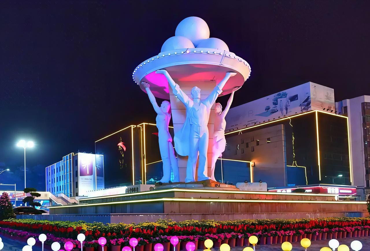 瞧见这尊茂名市雕，三个人共扛着四颗圆球，有人说这四颗球指代高信化电，有人说它们代